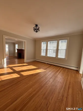 a view of an empty room with wooden floor and a window