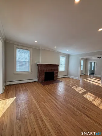 a view of empty room with wooden floor and fireplace