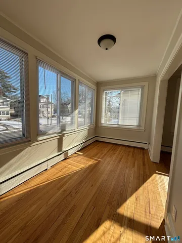 a view of an empty room with wooden floor and a window