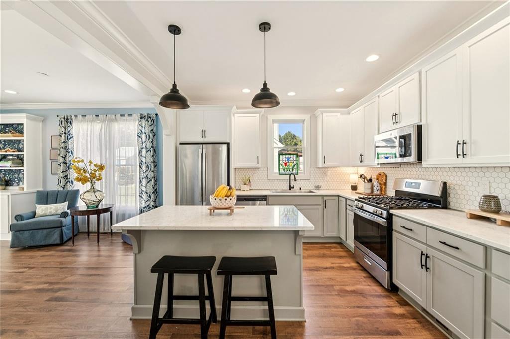 a kitchen with stainless steel appliances granite countertop a stove a sink dishwasher a stove a refrigerator white cabinets with wooden floor