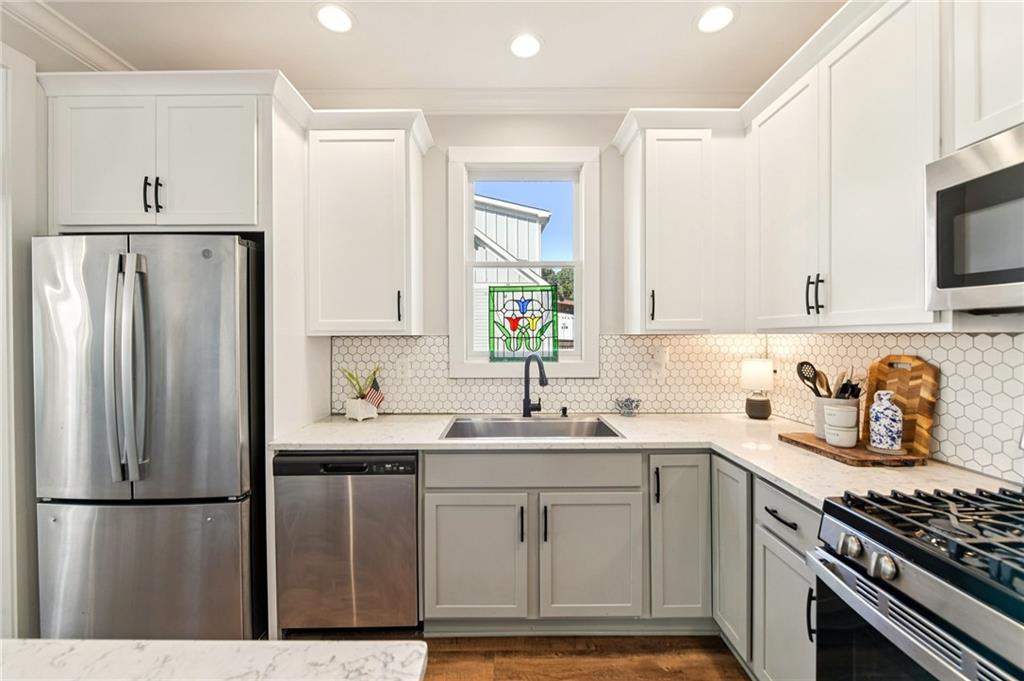 406 Bell Street Monroe, GA 30655 - Photo 13 of 60 a kitchen with refrigerator a stove a sink dishwasher and white cabinets with wooden floor