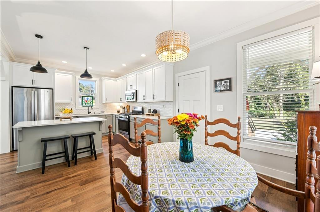 406 Bell Street Monroe, GA 30655 - Photo 14 of 60 a kitchen with stainless steel appliances kitchen island granite countertop a table chairs in it and wooden floors