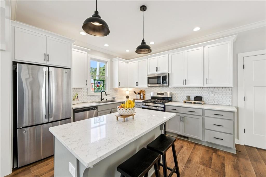 406 Bell Street Monroe, GA 30655 - Photo 10 of 60 a kitchen with stainless steel appliances granite countertop a refrigerator a sink dishwasher a stove a refrigerator and white cabinets with wooden floor