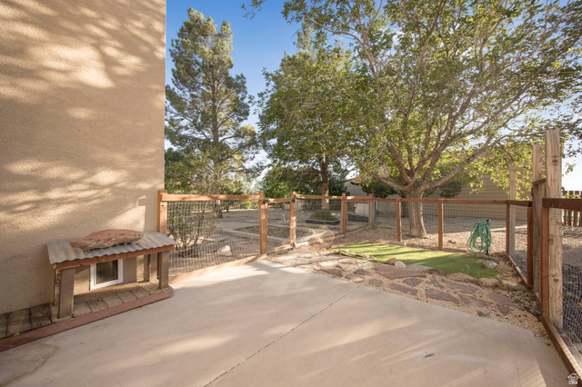 1440 West 100 South Virgin, UT 84779 - Photo 37 of 45 Outdoor patio area featuring a concrete surface, fenced perimeter, mature trees, and a gravel and stone landscape