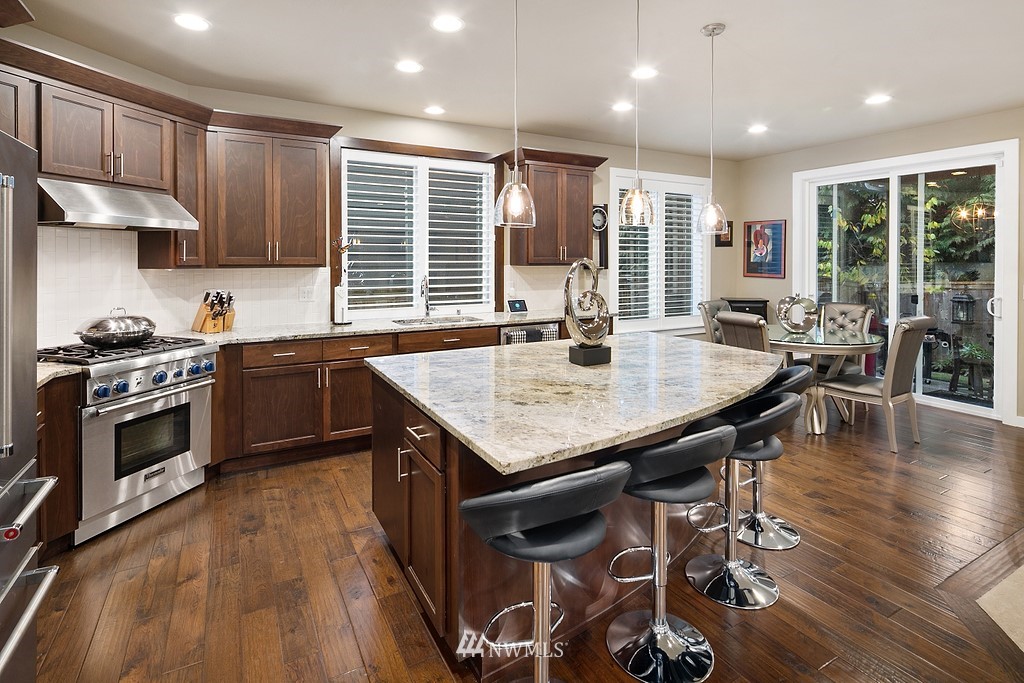 21920 37th Avenue Southeast Bothell, WA 98021 - Photo 13 of 39 a kitchen with stainless steel appliances granite countertop a stove top oven a sink dishwasher a dining table and chairs with wooden floor