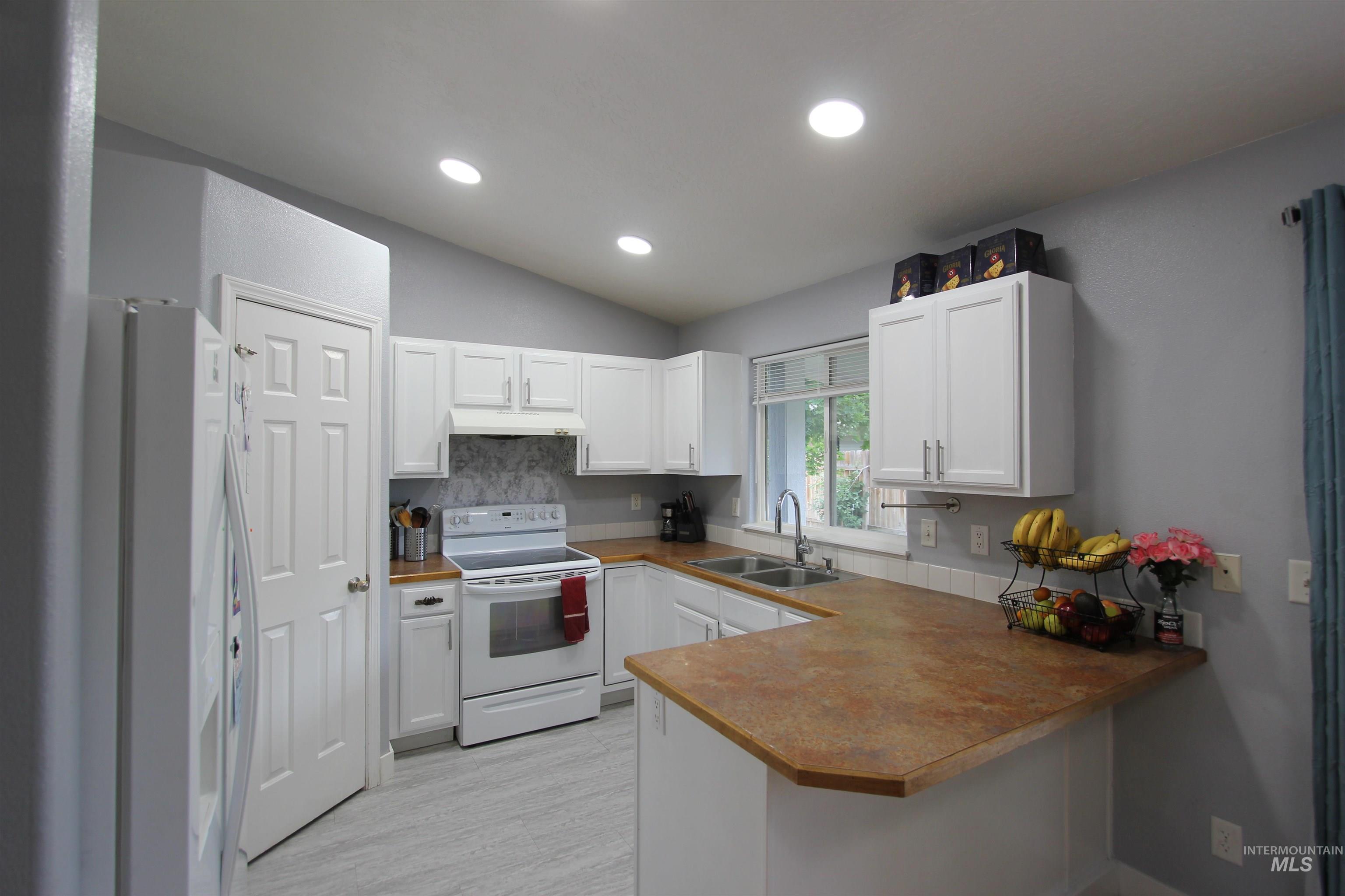 4816 Kadie Street Caldwell, ID 83607 - Photo 8 of 23 Kitchen featuring white cabinetry, light-toned backsplash, and a brown countertop with an integrated breakfast bar