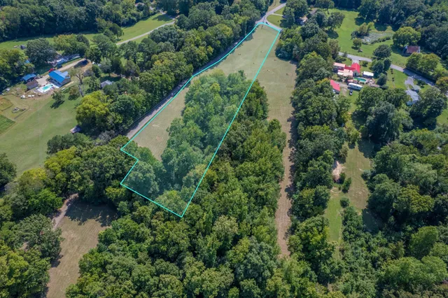 an aerial view of residential house with outdoor space and trees all around