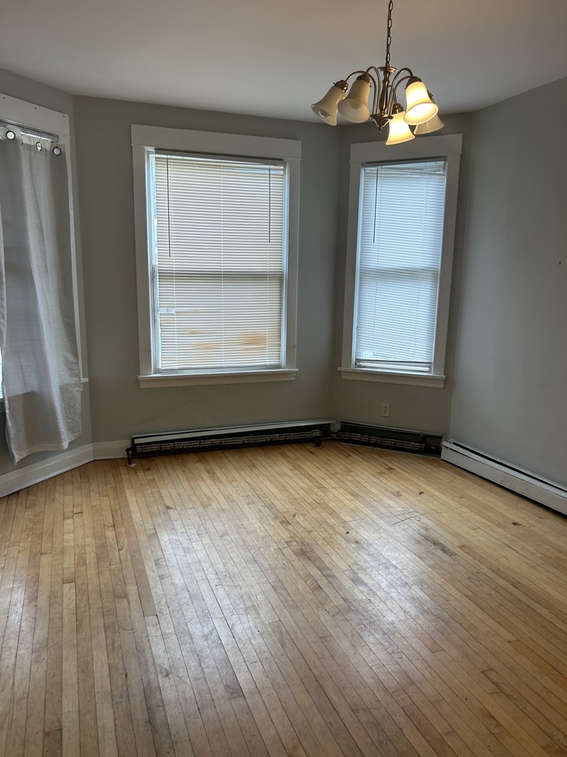 3718 North Spaulding Avenue Chicago, IL 60618 - Photo 8 of 18 an empty room with wooden floor exposed radiator and windows