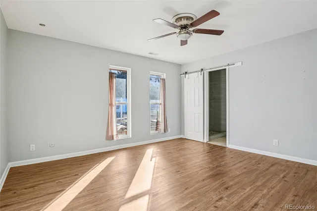 a view of an empty room with window and wooden floor