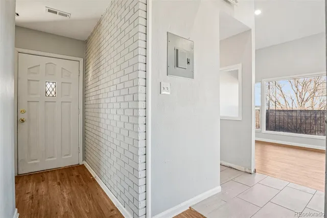 a view of a hallway with wooden floor and a bathroom