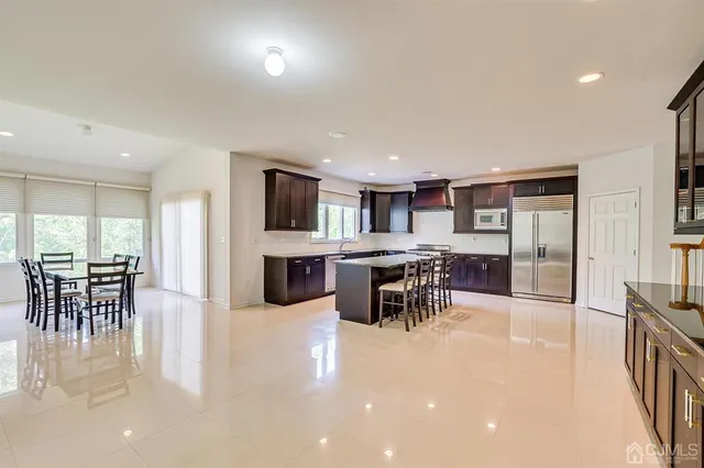 a kitchen with stainless steel appliances kitchen island granite countertop a table chairs sink and cabinets