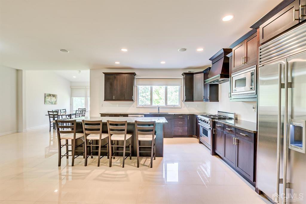 12 Hayduk Drive Edison, NJ 08820 - Photo 34 of 64 a kitchen with stainless steel appliances kitchen island granite countertop a table chairs sink and cabinets