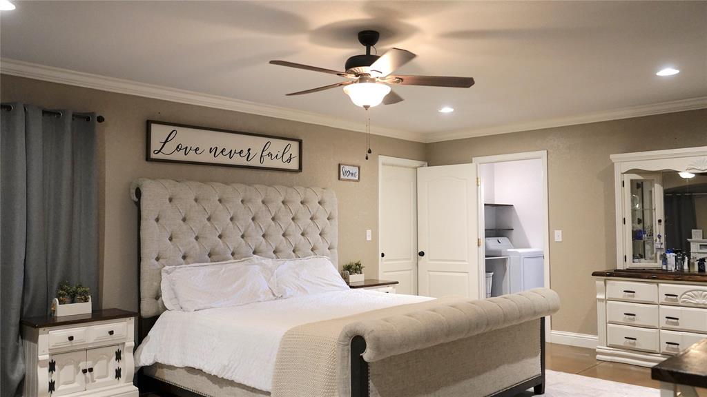 421 Weakes Street Eustace, TX 75124 - Photo 15 of 40 a bedroom with a large bed and a chandelier