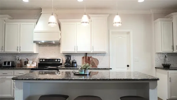 a kitchen with granite countertop a sink stainless steel appliances white cabinets and a window