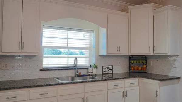 a kitchen with granite countertop white cabinets and a window