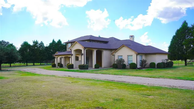a front view of a house with a yard and trees