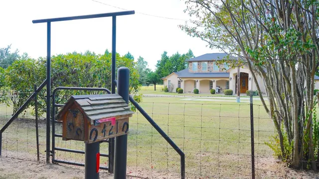 a front view of a house with a garden and trees