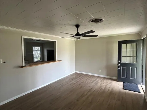 a view of an empty room with wooden floor and a window