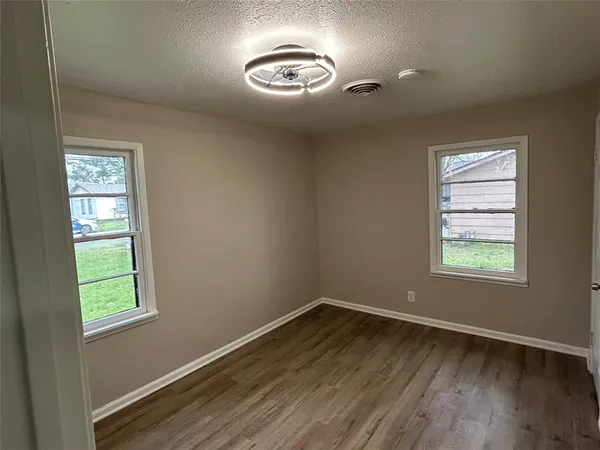 a view of an empty room with a window and wooden floor