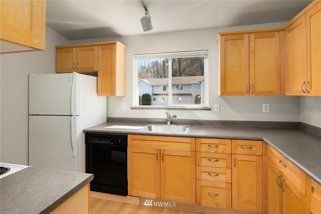 10838 East Riverside Drive, Unit C301 Bothell, WA 98011 - Photo 3 of 23 a kitchen with stainless steel appliances granite countertop a refrigerator a sink a stove with wooden cabinets and countertops
