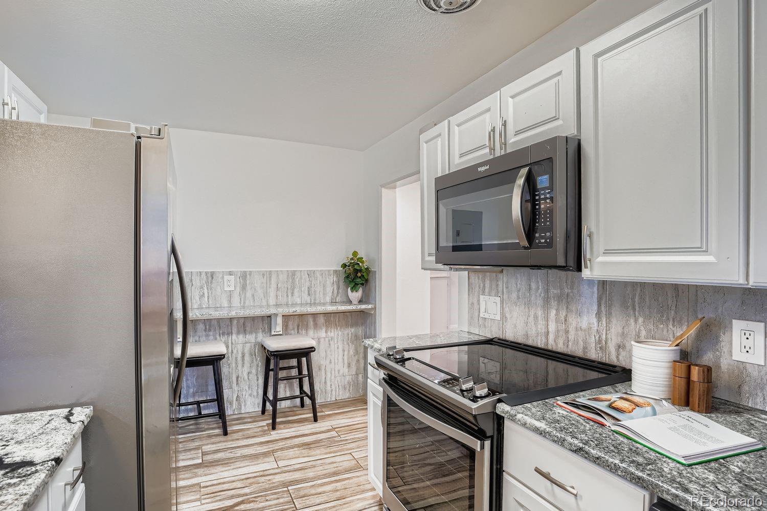 3822 Julian Street Denver, CO 80211 - Photo 12 of 28 a kitchen with granite countertop a stove top oven a sink dishwasher and white cabinets with wooden floor