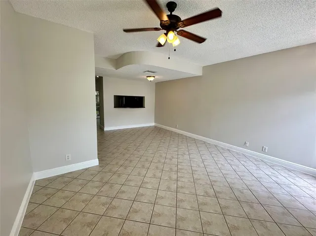 an empty room with a ceiling fan and carpet