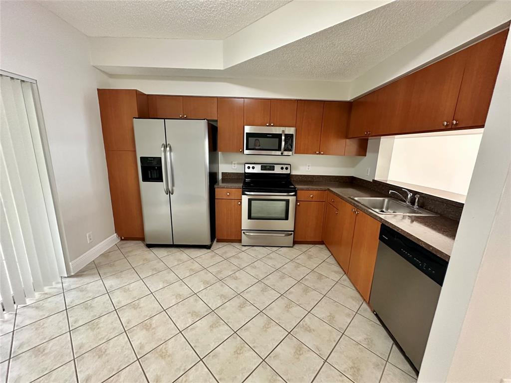 5660 Northwest 98th Way Coral Springs, FL 33076 - Photo 5 of 25 a kitchen with stainless steel appliances granite countertop a stove a sink and a refrigerator