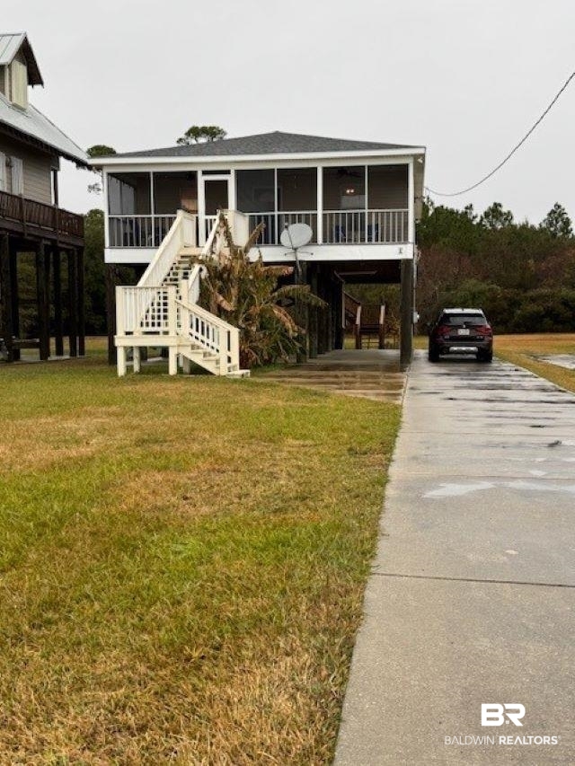 Beach home featuring a carport, a front lawn, and a sunroom