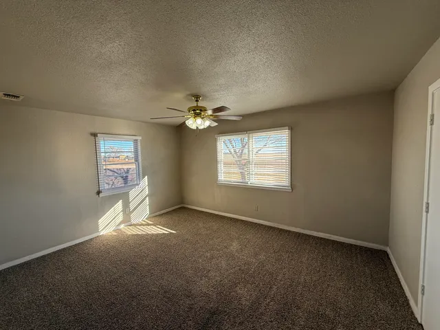 an empty room with windows and chandelier fan