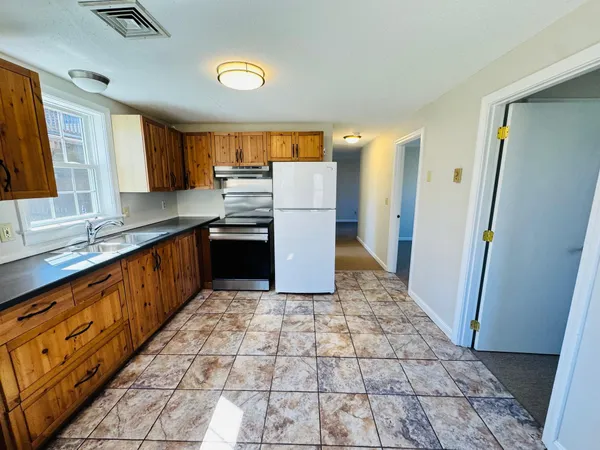 a large kitchen with stainless steel appliances granite countertop a refrigerator and a sink