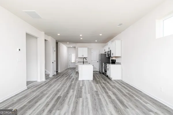 a view of a kitchen with kitchen island wooden floors appliances