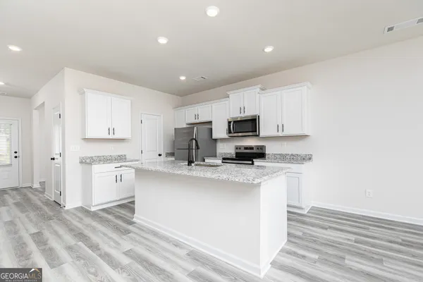 a kitchen with stainless steel appliances a refrigerator sink and white cabinets