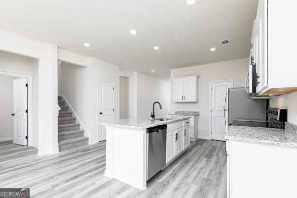a large kitchen with stainless steel appliances kitchen island granite countertop a stove and a sink