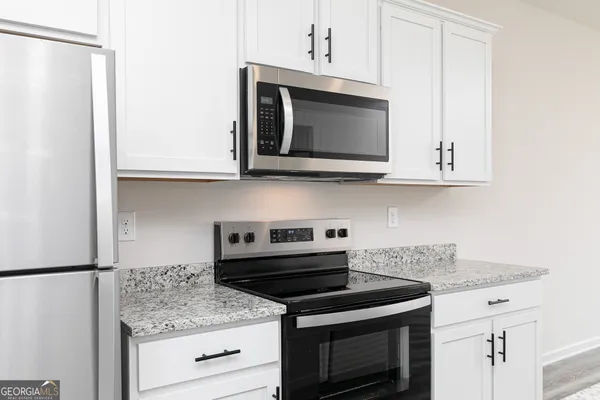 a kitchen with stainless steel appliances granite countertop white cabinets and a stove top oven