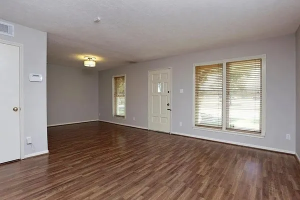 a view of an empty room with wooden floor and stairs