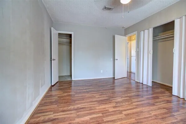 a view of an empty room with wooden floor and closet