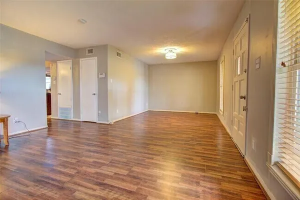 an empty room with wooden floor and windows