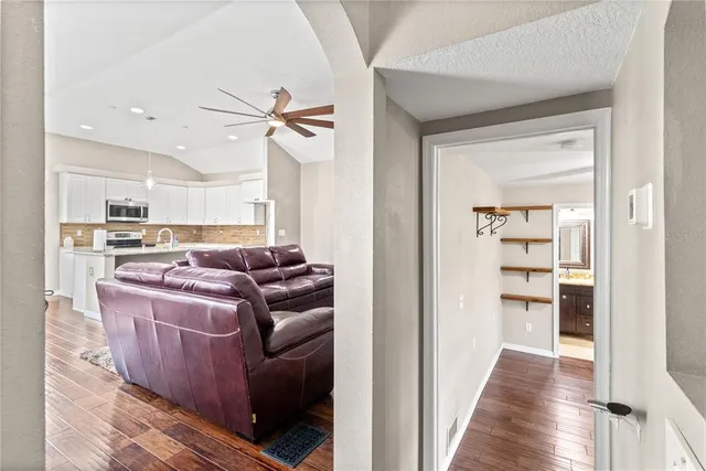 a living room with couches and kitchen view with wooden floor