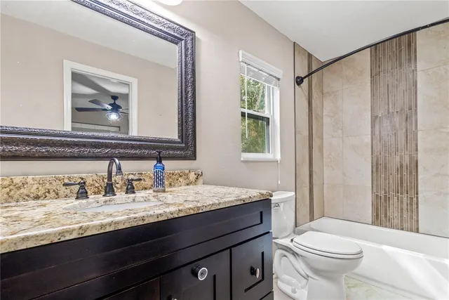a bathroom with a granite countertop sink mirror vanity and toilet