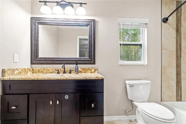 a bathroom with a granite countertop toilet sink and mirror