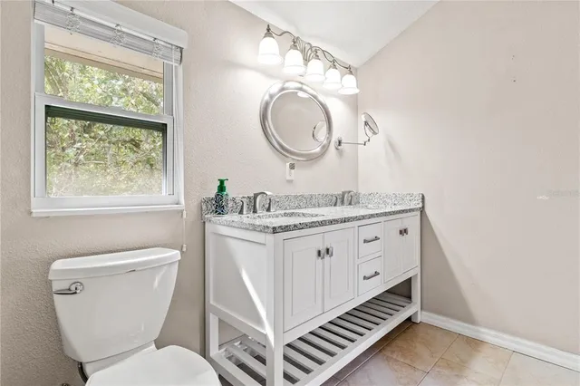 a bathroom with a granite countertop toilet a sink and a mirror