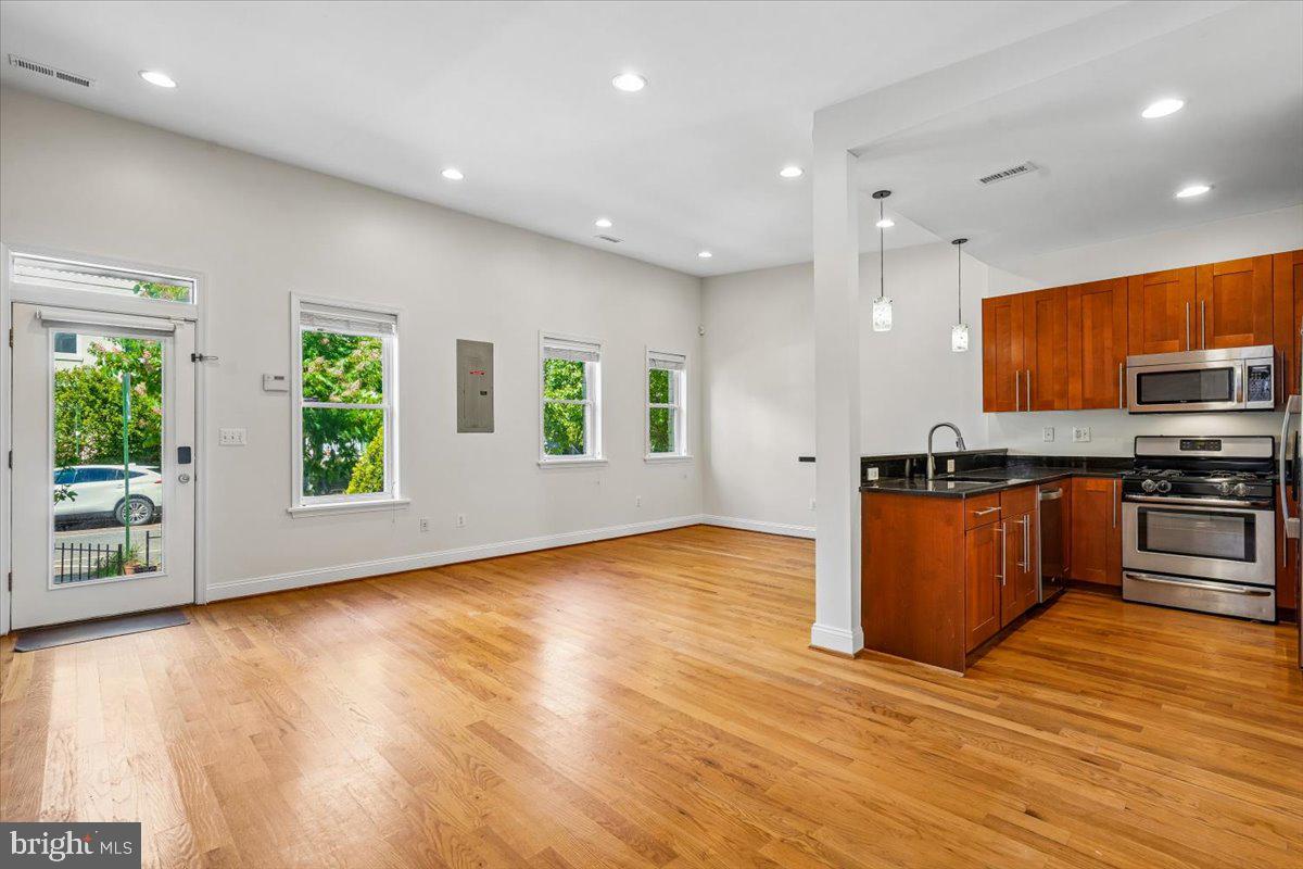 1339 C Street Northeast Washington, DC 20002 - Photo 5 of 24 a view of kitchen with stainless steel appliances granite countertop a stove top oven a sink dishwasher a microwave oven and a large window with wooden floor