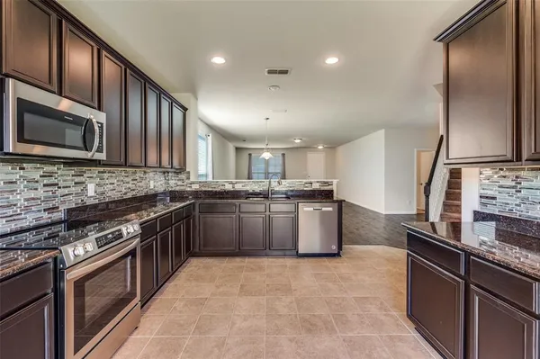 a kitchen with stainless steel appliances granite countertop a stove a sink and a microwave