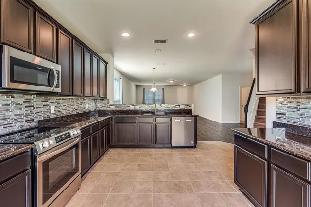 a kitchen with stainless steel appliances granite countertop a stove a sink and a microwave