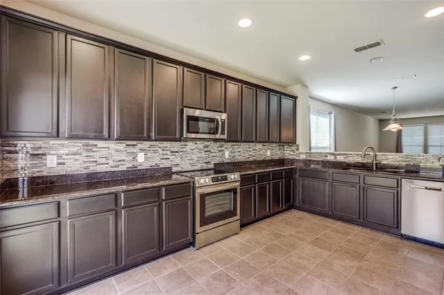 a large kitchen with stainless steel appliances granite countertop a stove a sink dishwasher a refrigerator and a microwave