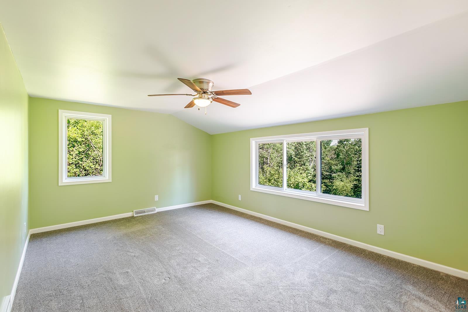 29 Ridge Road Esko, MN 55733 - Photo 20 of 41 Spacious room featuring vaulted ceilings, a ceiling fan with light fixture, gray carpet flooring, and multiple windows with white trim