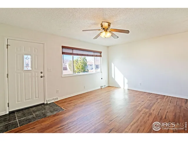 an empty room with wooden floor chandelier fan and windows