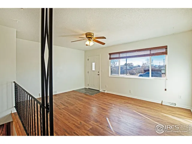 a view of an empty room with window and wooden floor