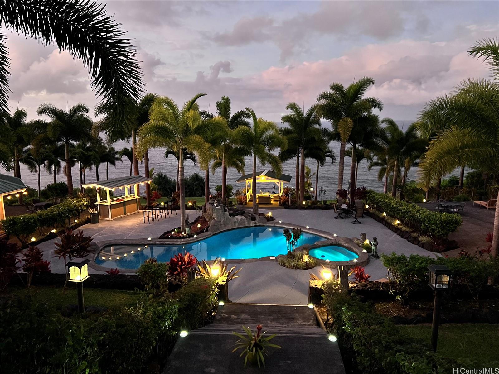 31-212 Hawaii Belt Road Hakalau, HI 96710 - Photo 23 of 25 Twilight view of the estate’s pool, glowing lights, and ocean backdrop—pure island magic