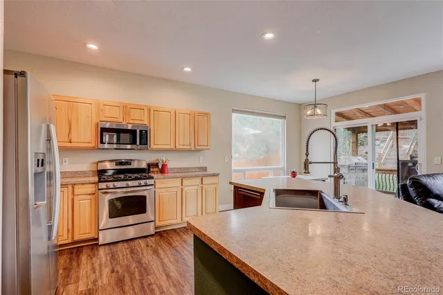 a large kitchen with stainless steel appliances granite countertop a stove a sink dishwasher a refrigerator and a stove with wooden floor